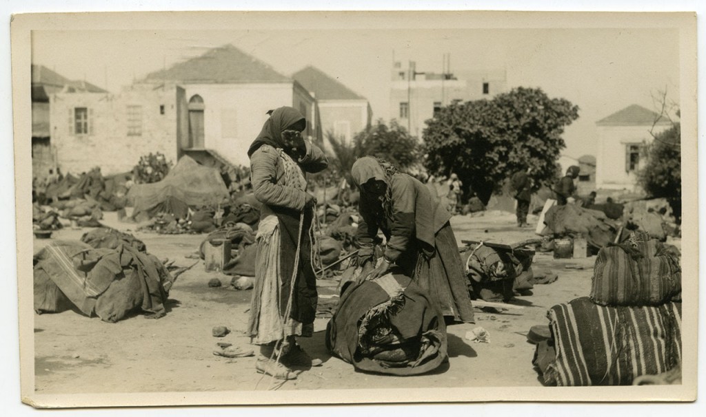 Two refugee women pack their major belongings into bundles.