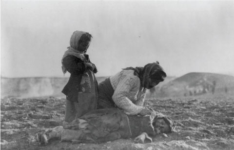 Woman and child standing over a child who died within sight of safety in Aleppo