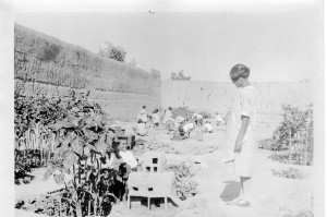 Children in the garden at Alexandropol. An older girl watches a younger boy build a mud house. 