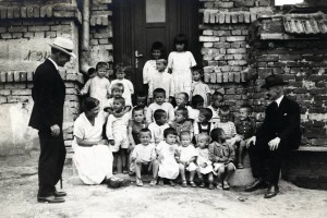 Barclay Acheson with two relief workers and a group of young children sitting on steps. The building is marked 