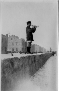 Older boy with a trumpet standing on a low orphanage wall at Alexandropol.
